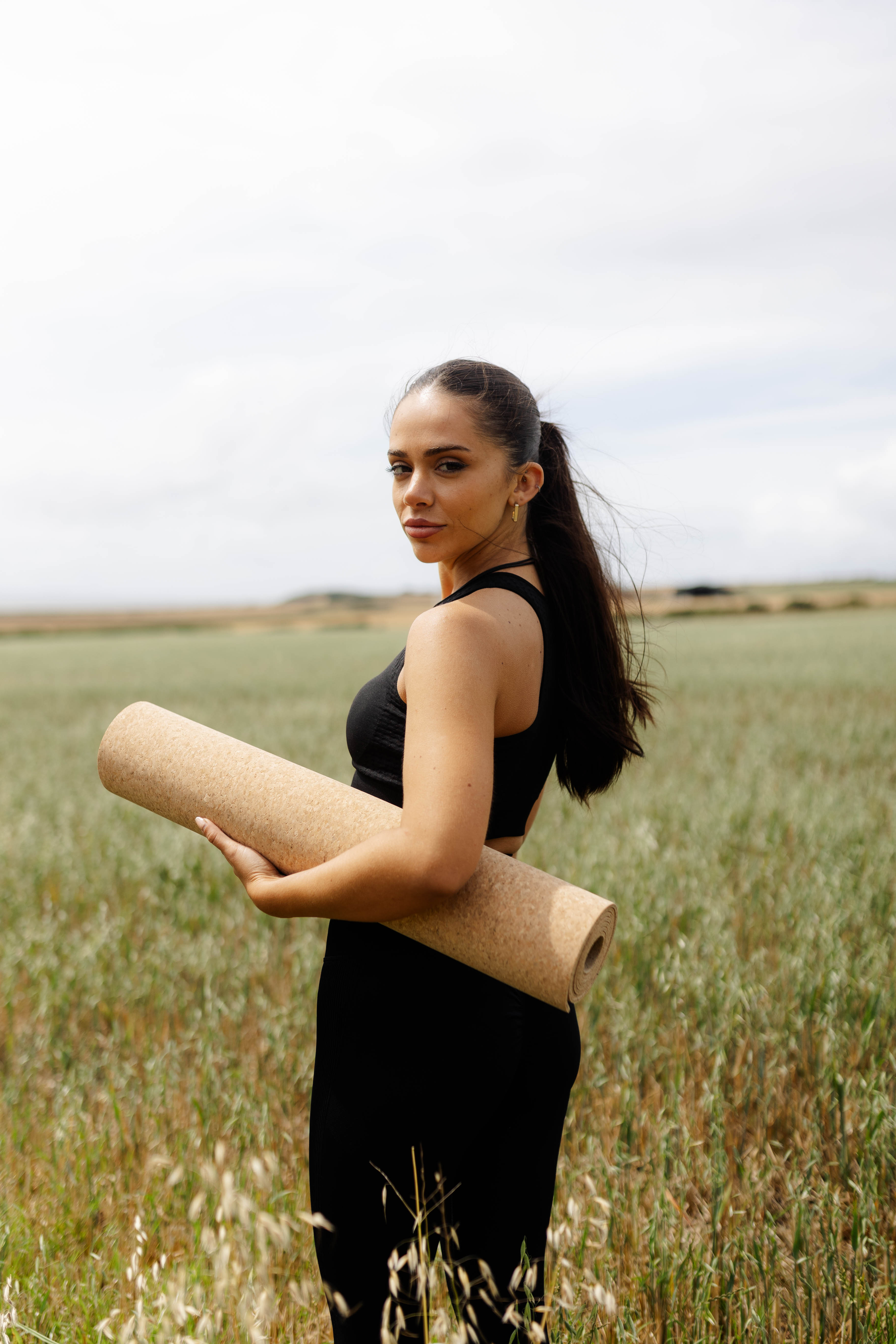 Person holding a rolled cork mat in a natural outdoor field
